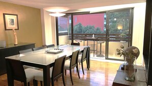 A dining area with a large table, chairs, a vase with flowers, and a view through a large window. - 70ft from the Tiffany's store in Polanco, near the World Cup, 2-bedroom apartment with a balcony. (Ciudad de México)