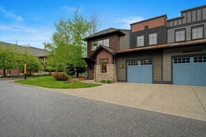 A two-story building with a garage and a stone foundation. - Town Center Home with Private Hot Tub (Gallatin Gateway)