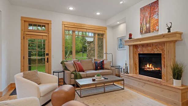 Una sala de estar con chimenea, un sofá, una mesa de centro y ventanas amplias.