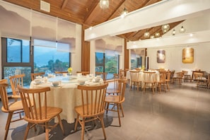 A dining area with round tables, wooden chairs, and large windows with mountain views. - Fanjing Mountain Xingyi Yunshe Homestay (Tongren)