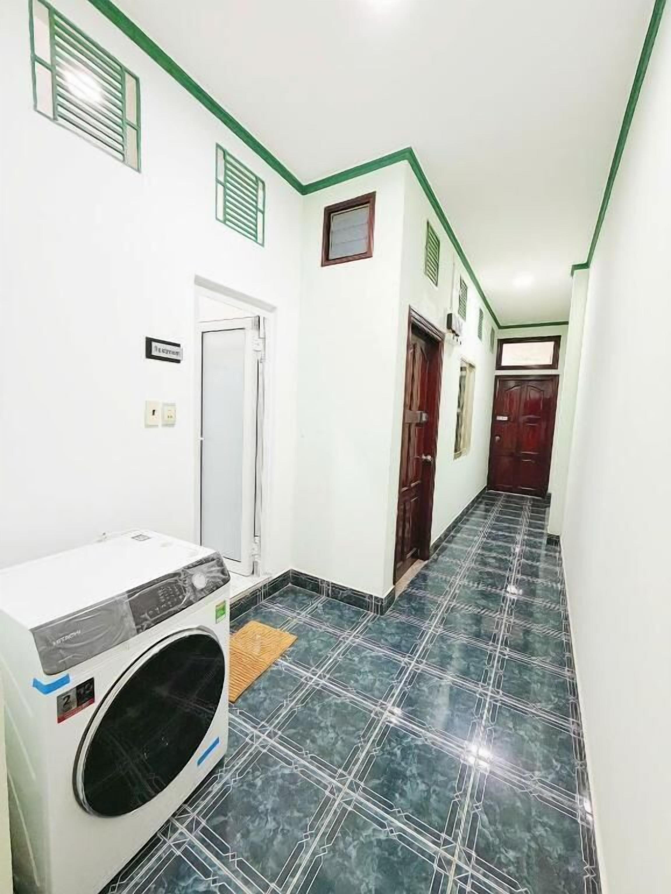 A hallway with a washing machine, a door, and a tiled floor.