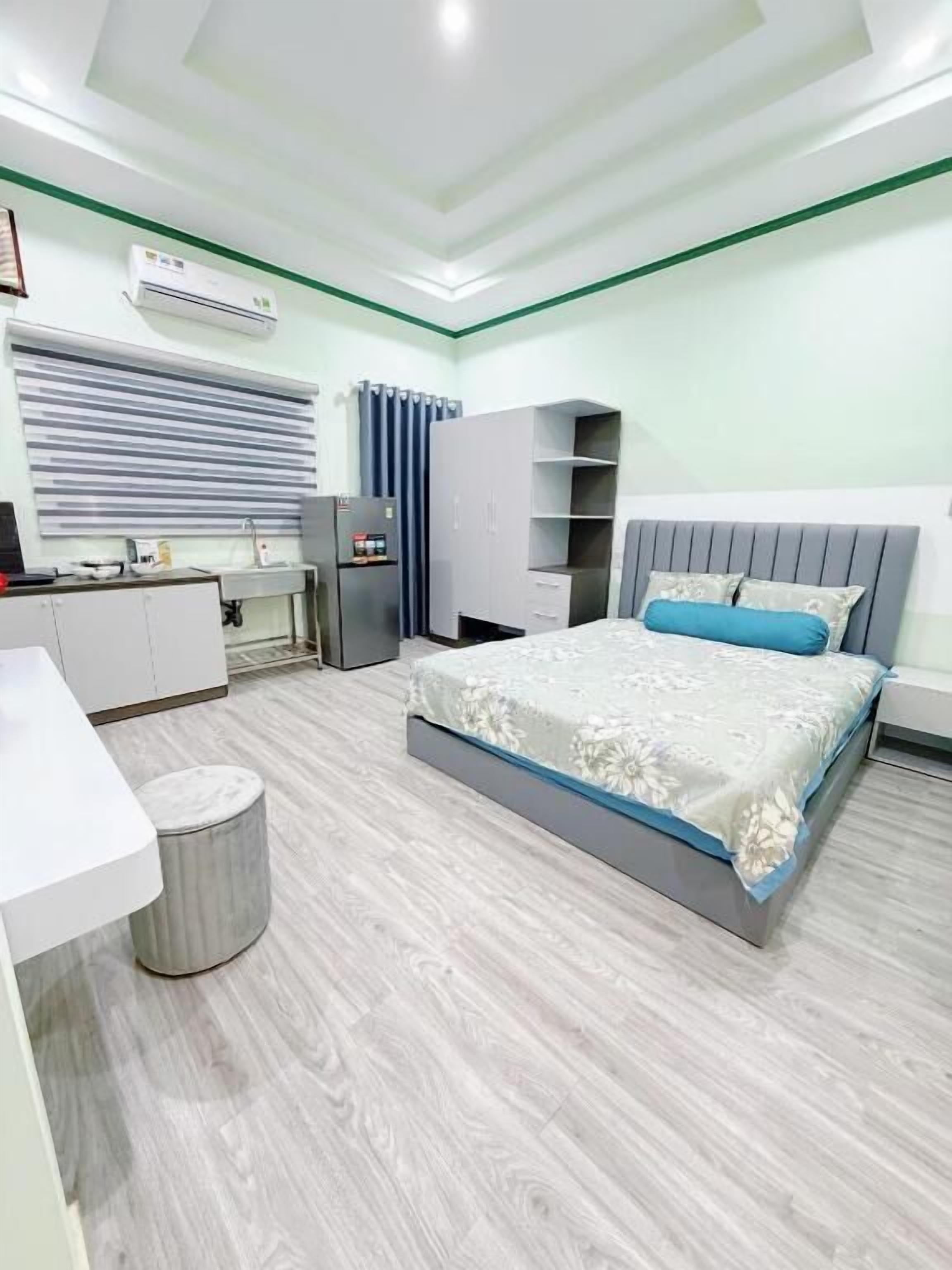 A modern bedroom with a bed, bedside tables, a wardrobe, and a small round ottoman.