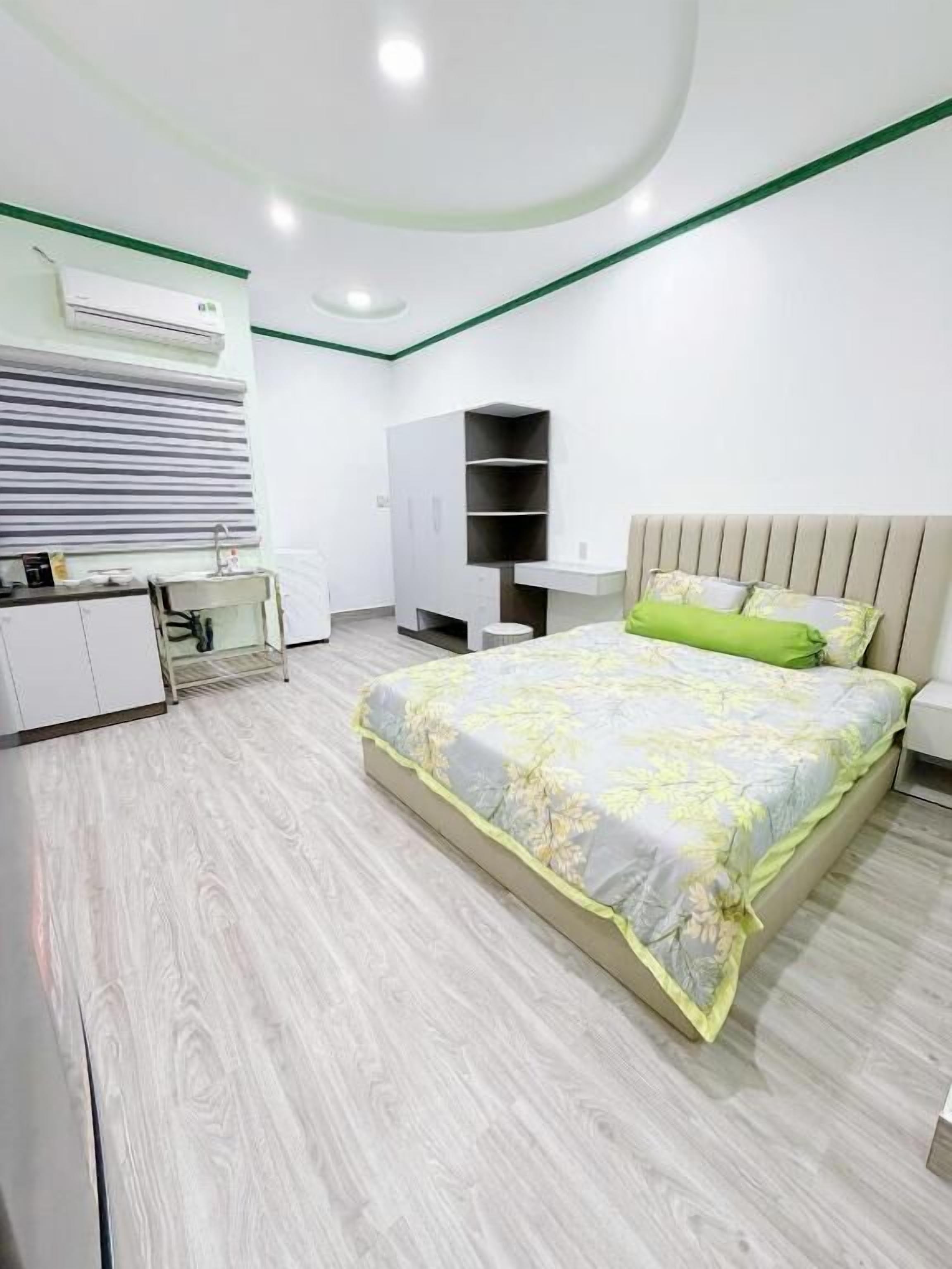 Un dormitorio moderno con cama, mesita de noche, armario y una pequeña zona de kitchenette.
