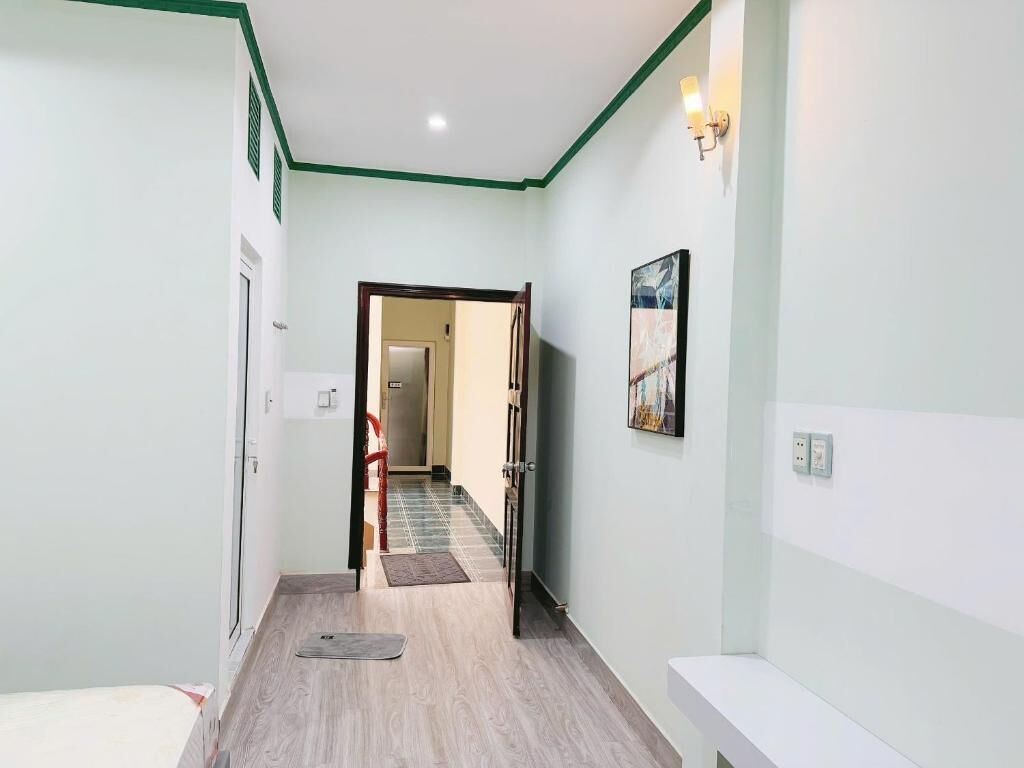 Un pasillo con suelo de madera, una puerta a la izquierda y una lámpara de pared a la derecha.