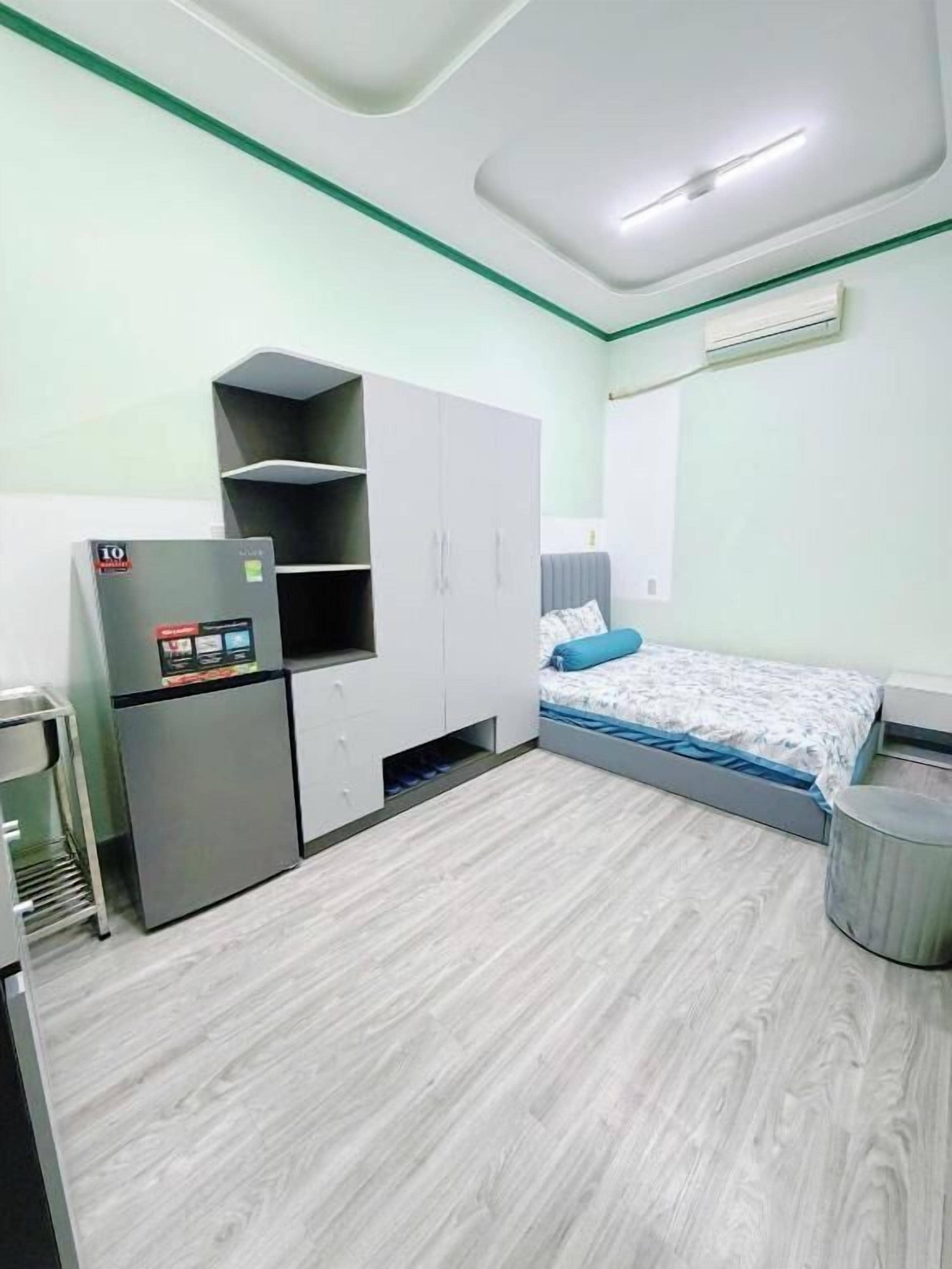 A compact room with a bed, a kitchenette, and a small seating area.