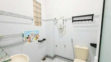 Une petite salle de bain avec des toilettes, un lavabo et une douche.