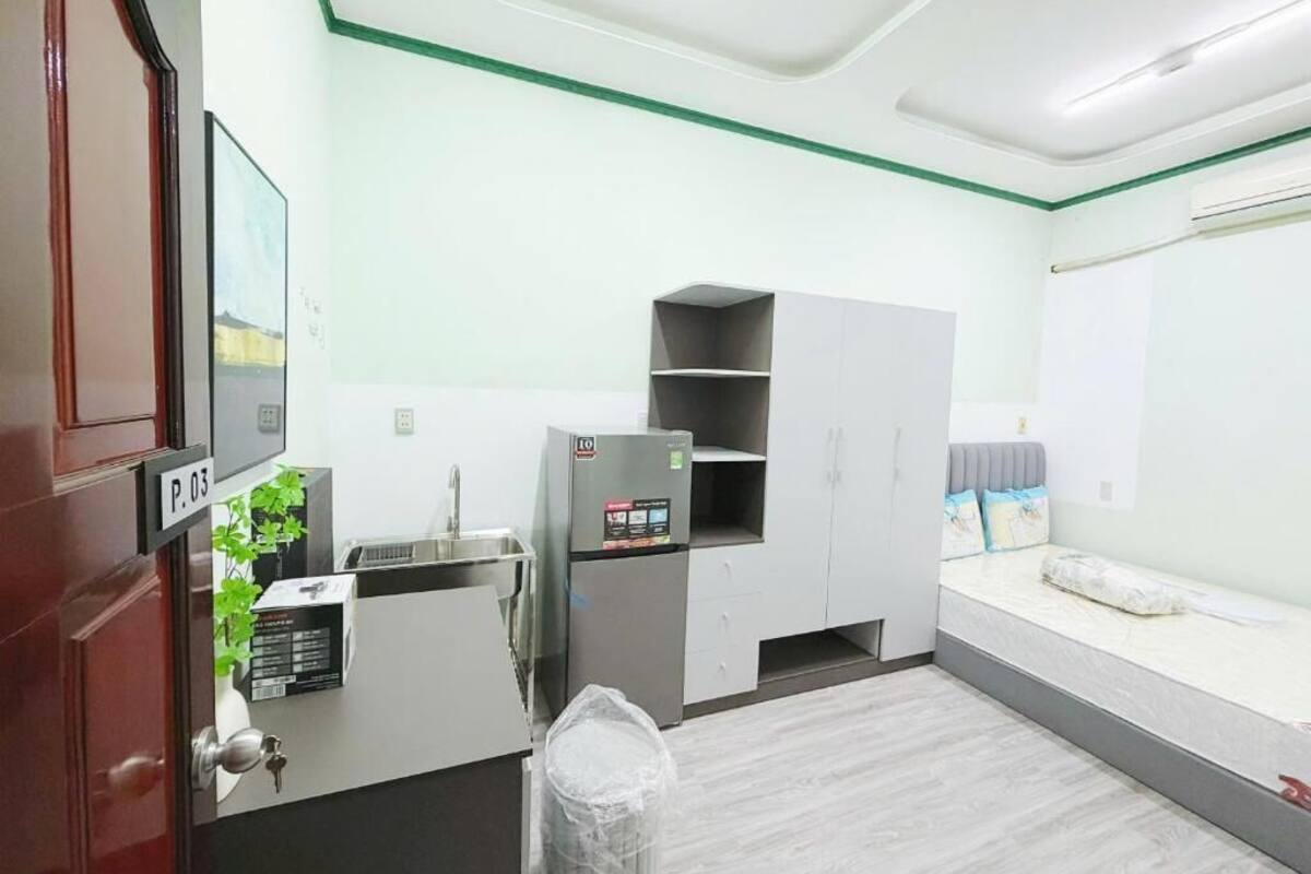 Una habitación compacta con kitchenette, una cama y un ventanal pequeño.