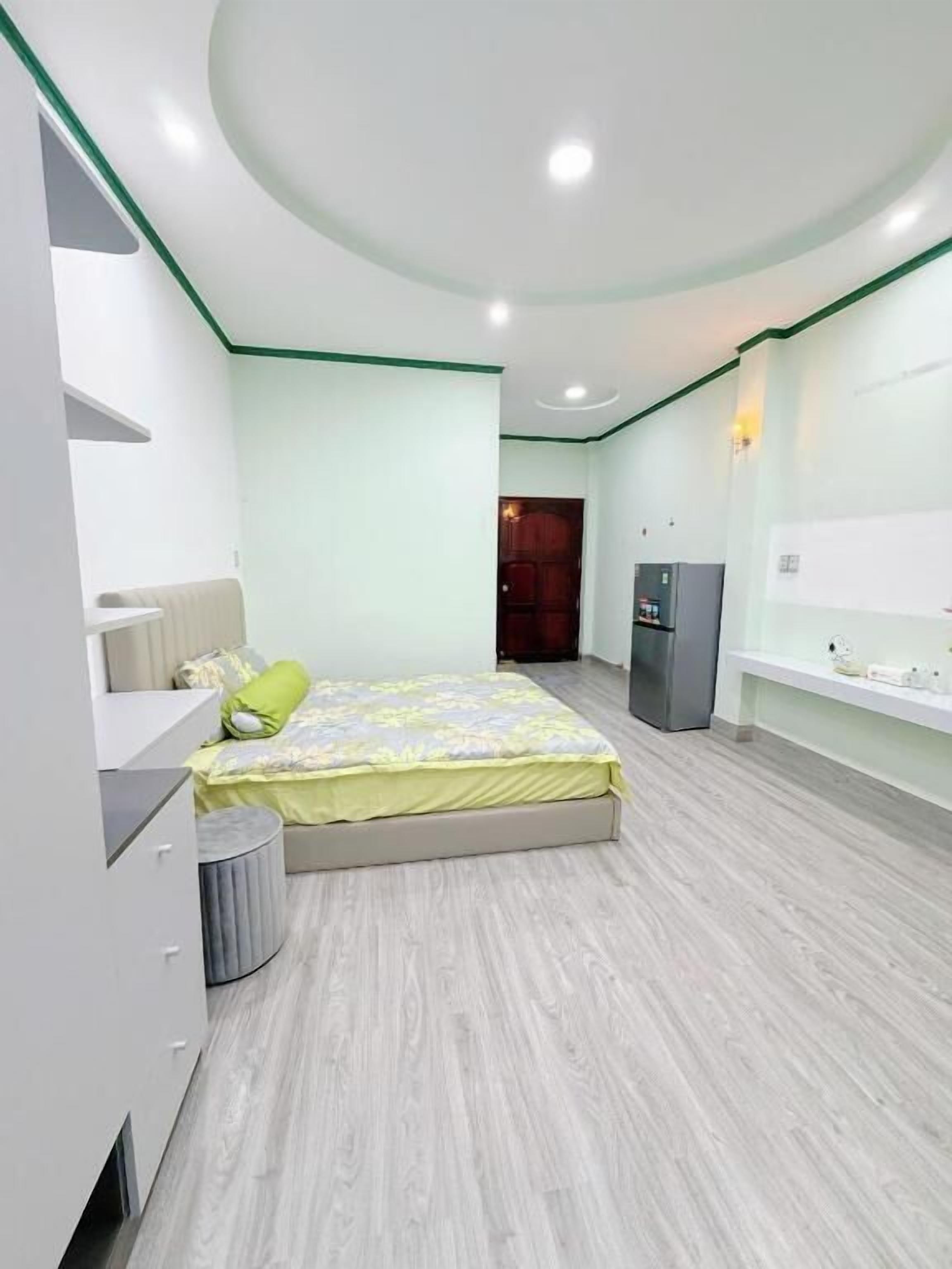 A bedroom with a bed, bedside table, and a small trash bin.