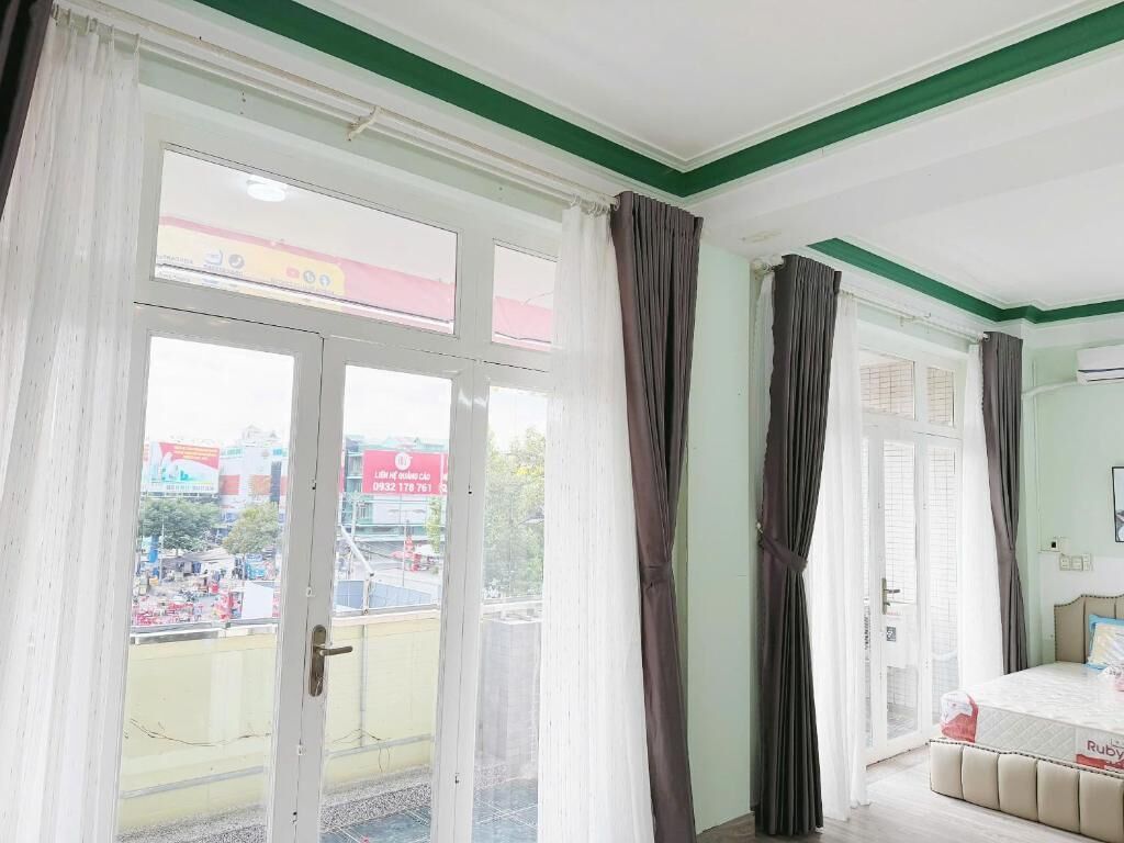 Habitación con un gran ventanal corredera, una cama y vistas a una zona comercial exterior.