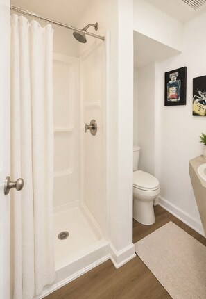 Ein Badezimmer mit Dusche, Toilette, Waschbecken und einem gerahmten Bild an der Wand.
