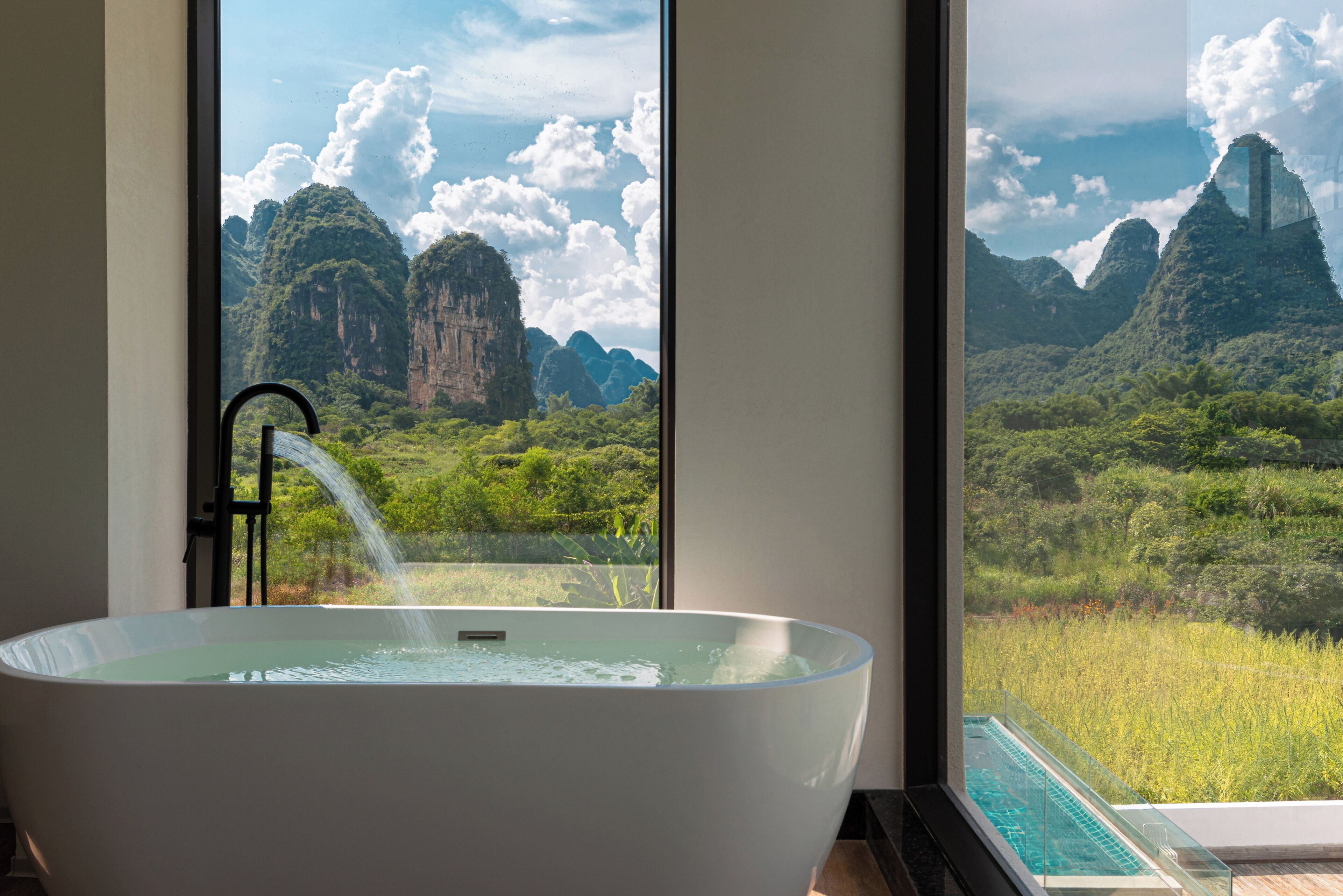 Una bañera con función de cascada y vistas a un paisaje montañoso a través de amplios ventanales.