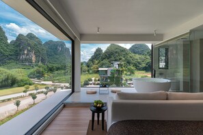 A modern room with a large window, a bathtub, and a sofa. - YangShuo Waterside Boutique Hotel (Guilin)