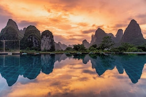 A serene landscape with a reflective pool, limestone karst formations, and lush greenery. - YangShuo Waterside Boutique Hotel (Guilin)
