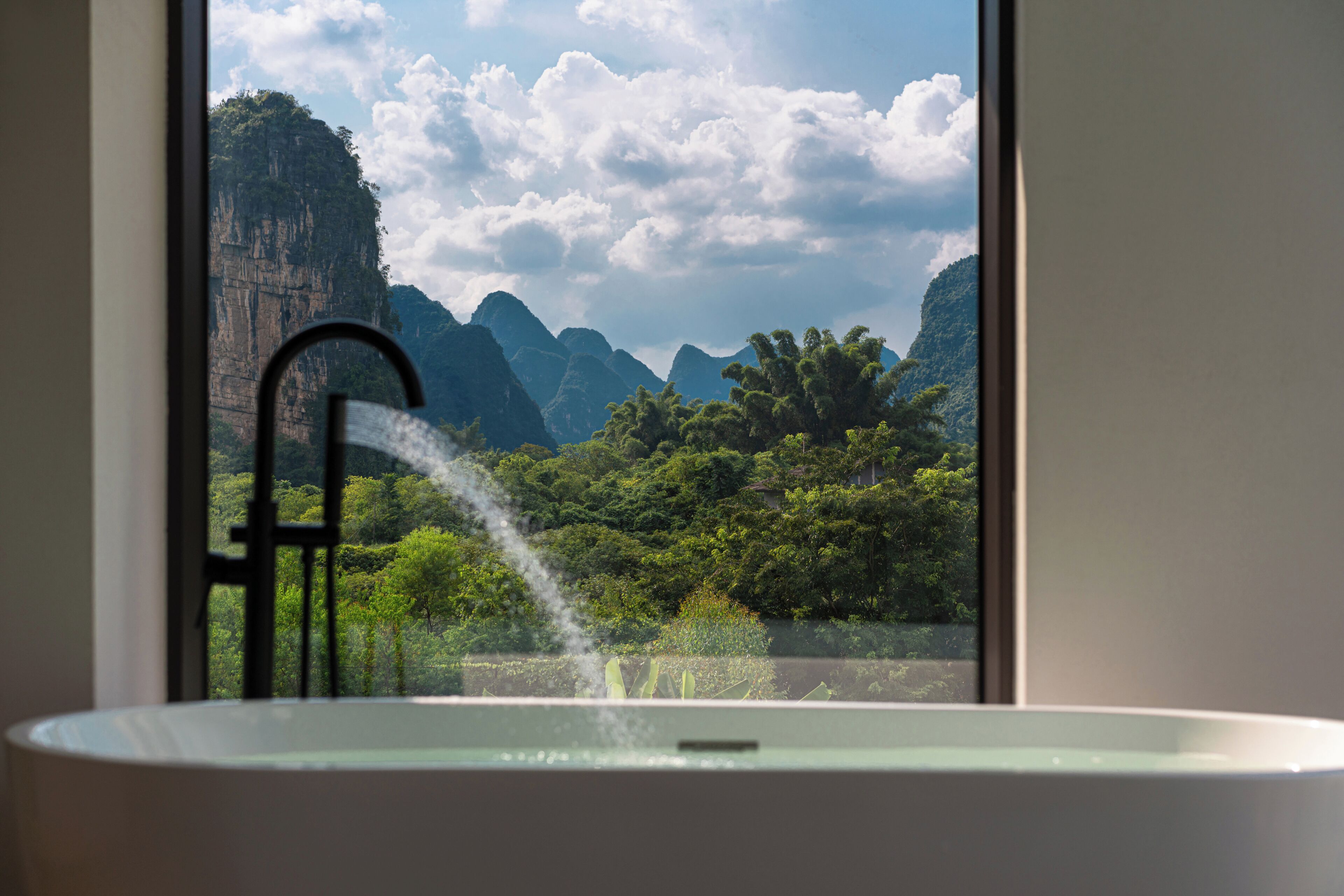 A bathtub with a view of a mountainous landscape through a window.