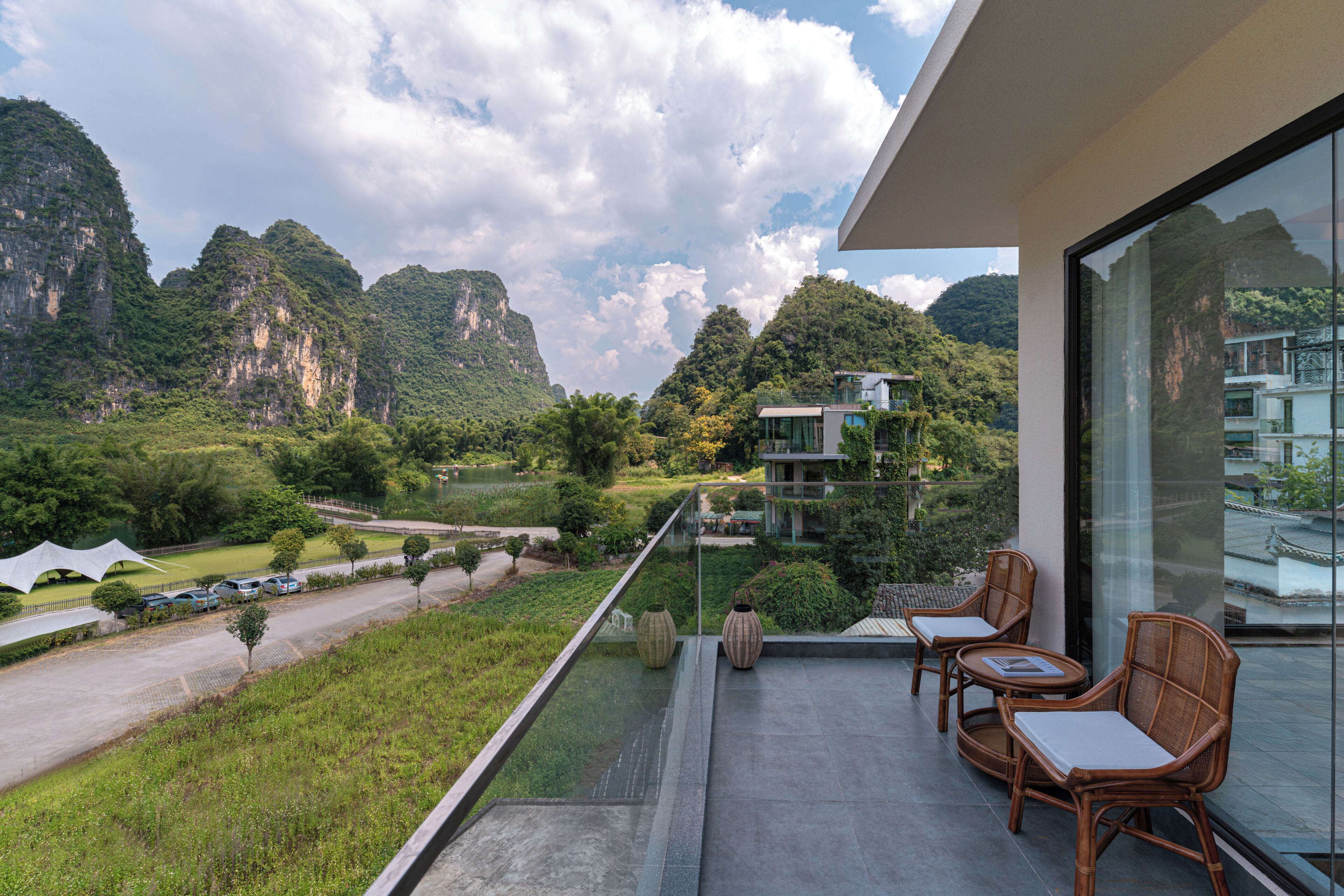 A balcony with wicker chairs and a view of a mountainous landscape.