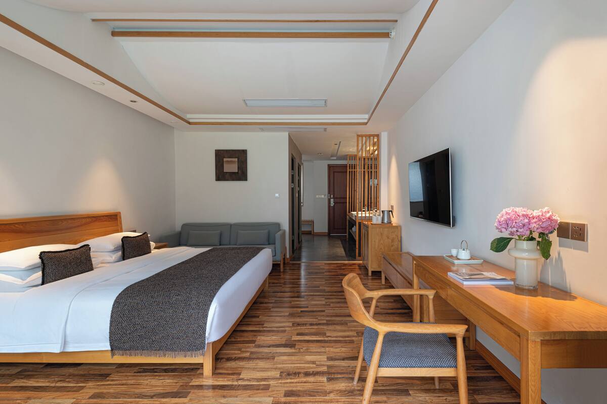 Ein Hotelzimmer mit Bett, Schreibtisch, Stuhl, Fernseher und einem sichtbaren Badezimmer im Hintergrund.