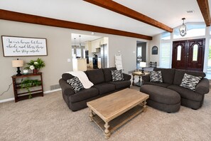 A living room with a sectional sofa, a wooden coffee table, and a decorative wall sign. - Private Indoor Pool + Slide Sleeps 18+ Lake Cumberland (Somerset)