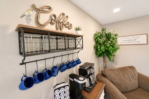 Una estación de café con una máquina de café, tazas y un cartel que dice 'Coffee'.