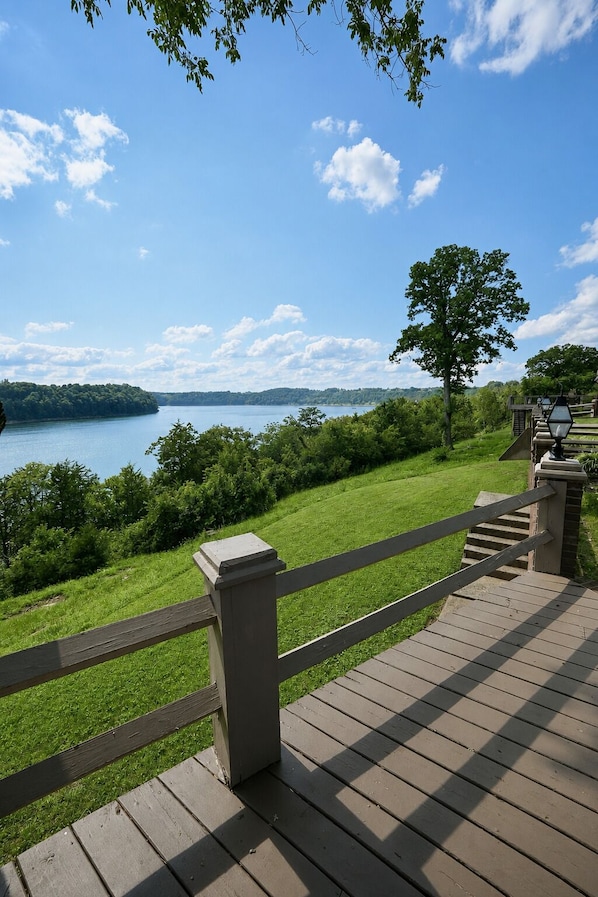 A wooden deck with a view of a lake and distant land.
