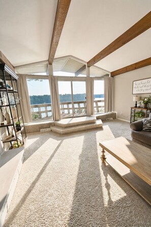 A spacious room with a high ceiling, large windows overlooking a body of water, a wooden bench, and a bookshelf. - Private Indoor Pool + Slide Sleeps 18+ Lake Cumberland (Somerset)