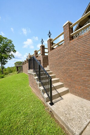 A brick staircase with a black metal railing leading up to a building with a brick facade.