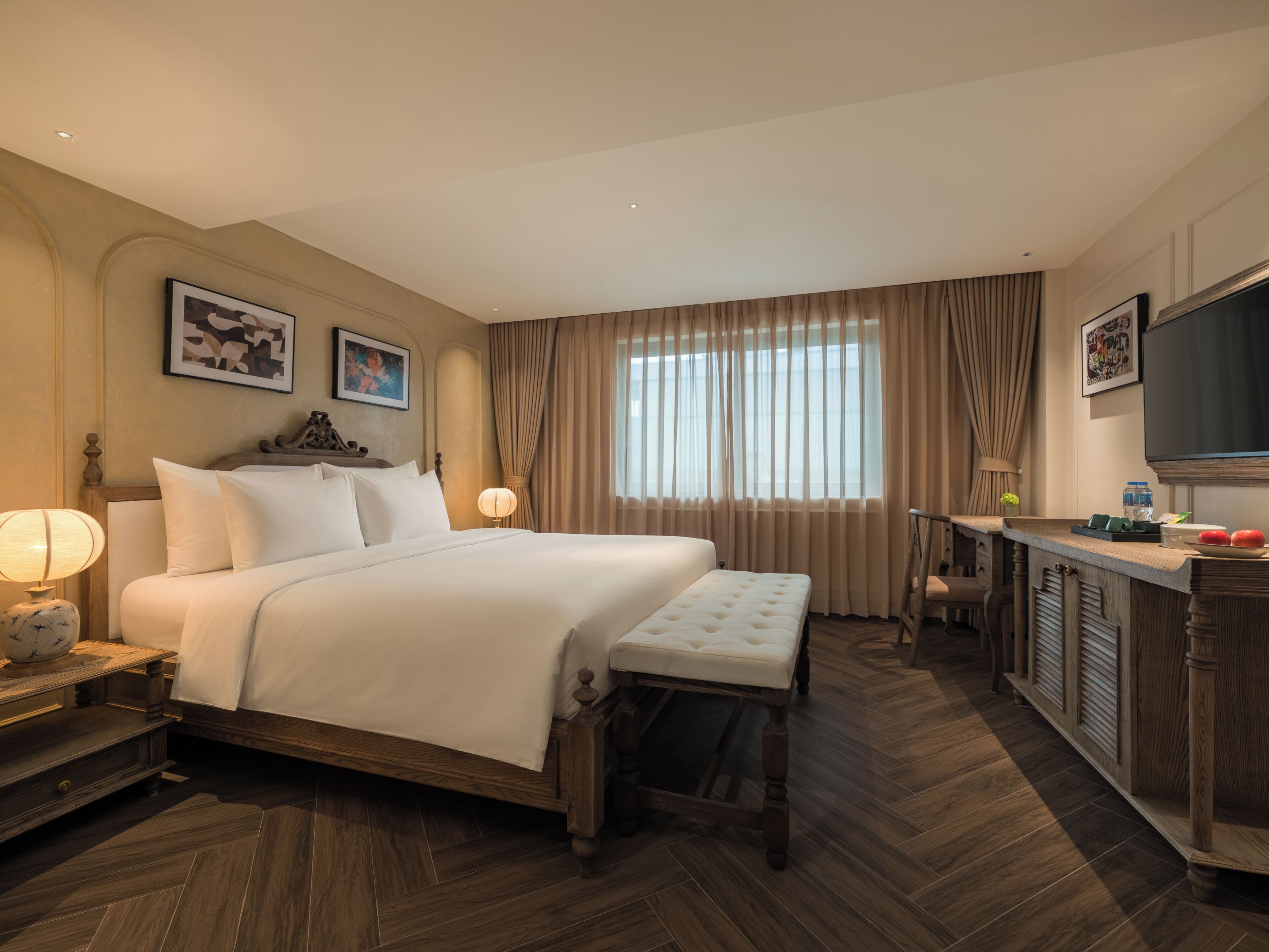 Een hotelkamer met een groot bed, nachtkastjes, een bureau en een televisie.