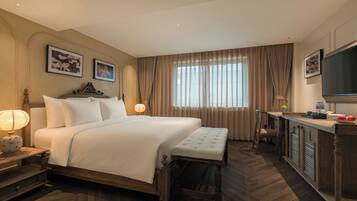 Een hotelkamer met een groot bed, nachtkastjes, een bureau en een televisie.