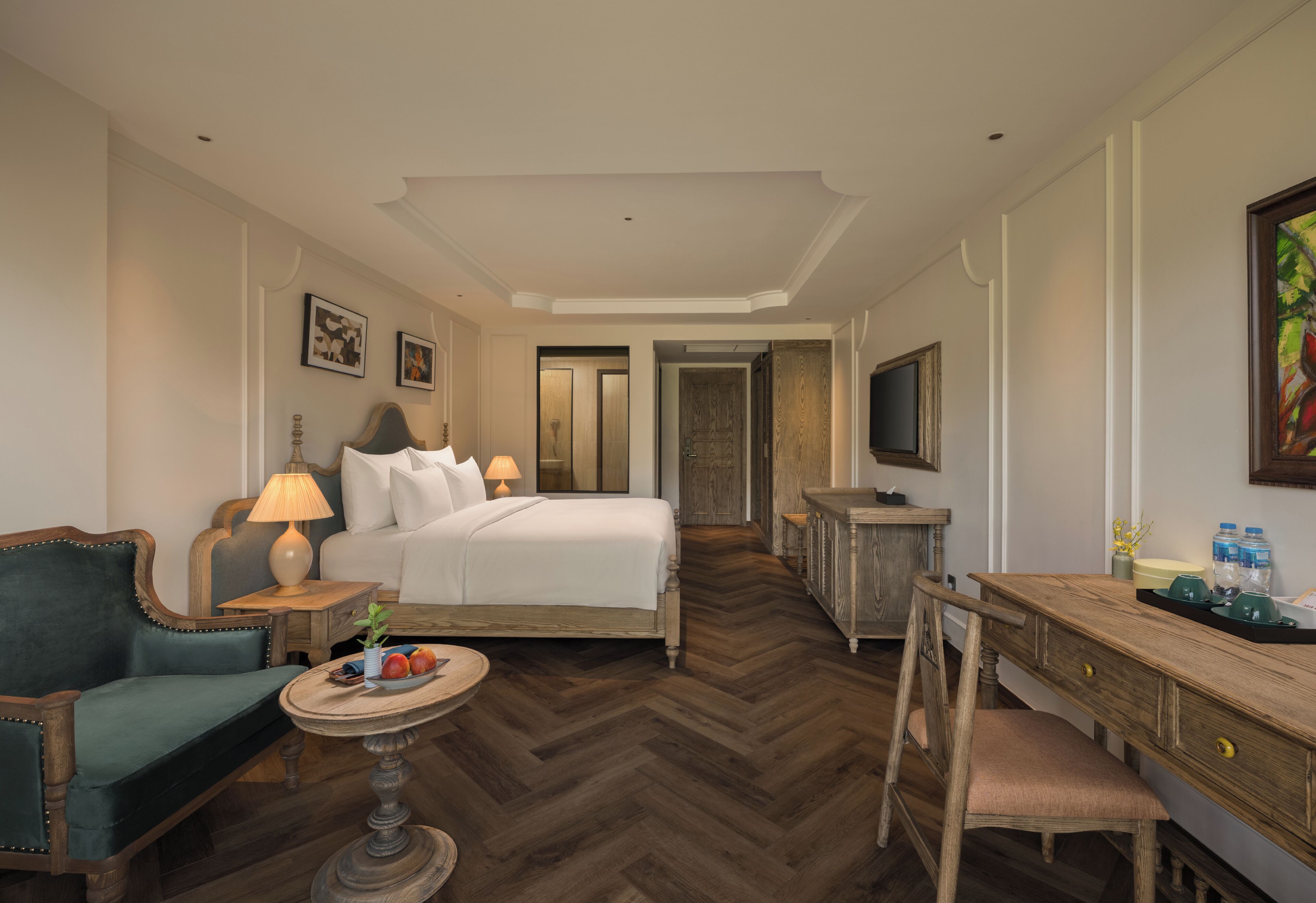 Habitación de hotel con cama, escritorio, silla, una mesita y televisor.