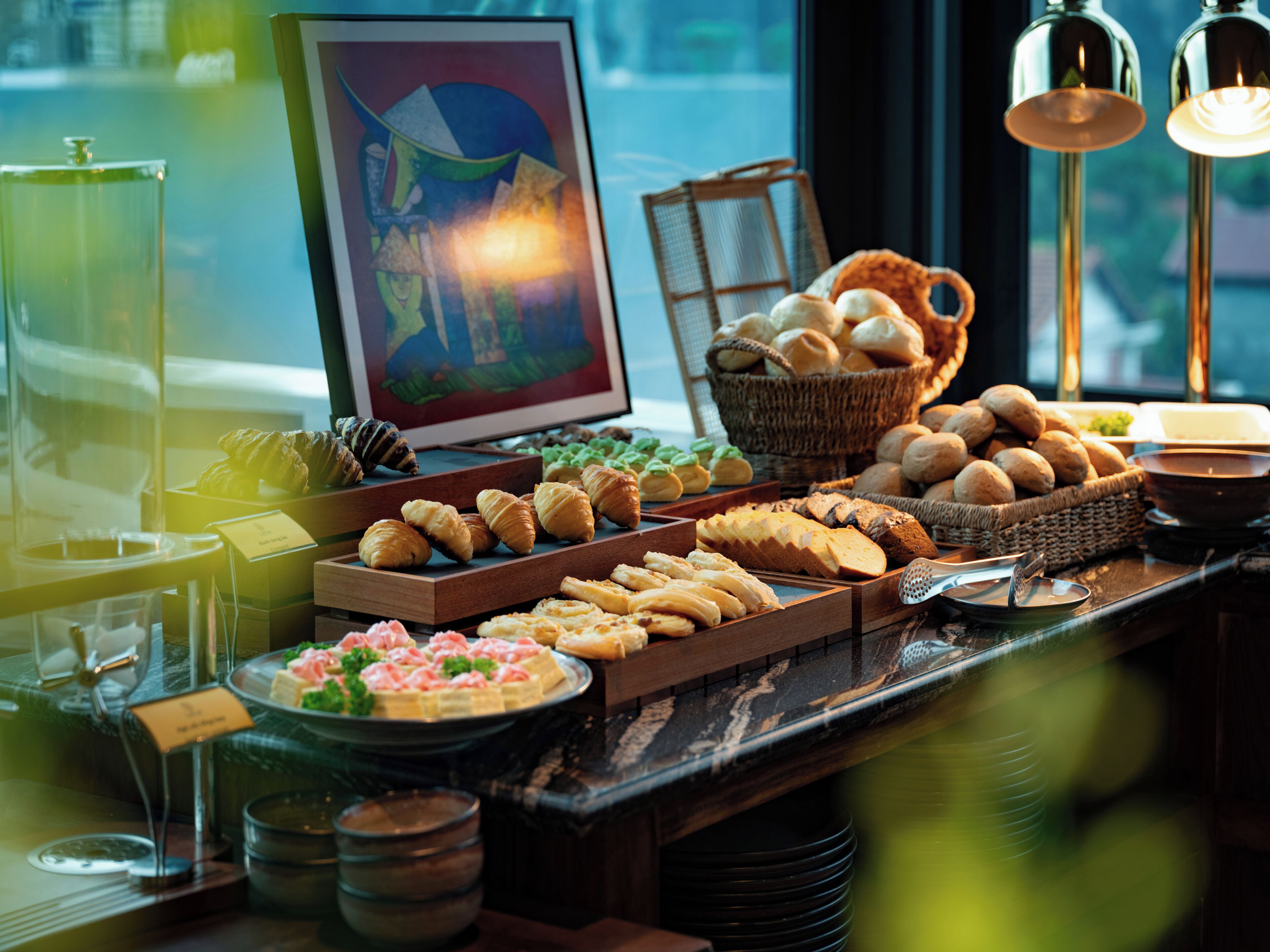 Una mesa de buffet con distintos alimentos y una obra de arte enmarco.