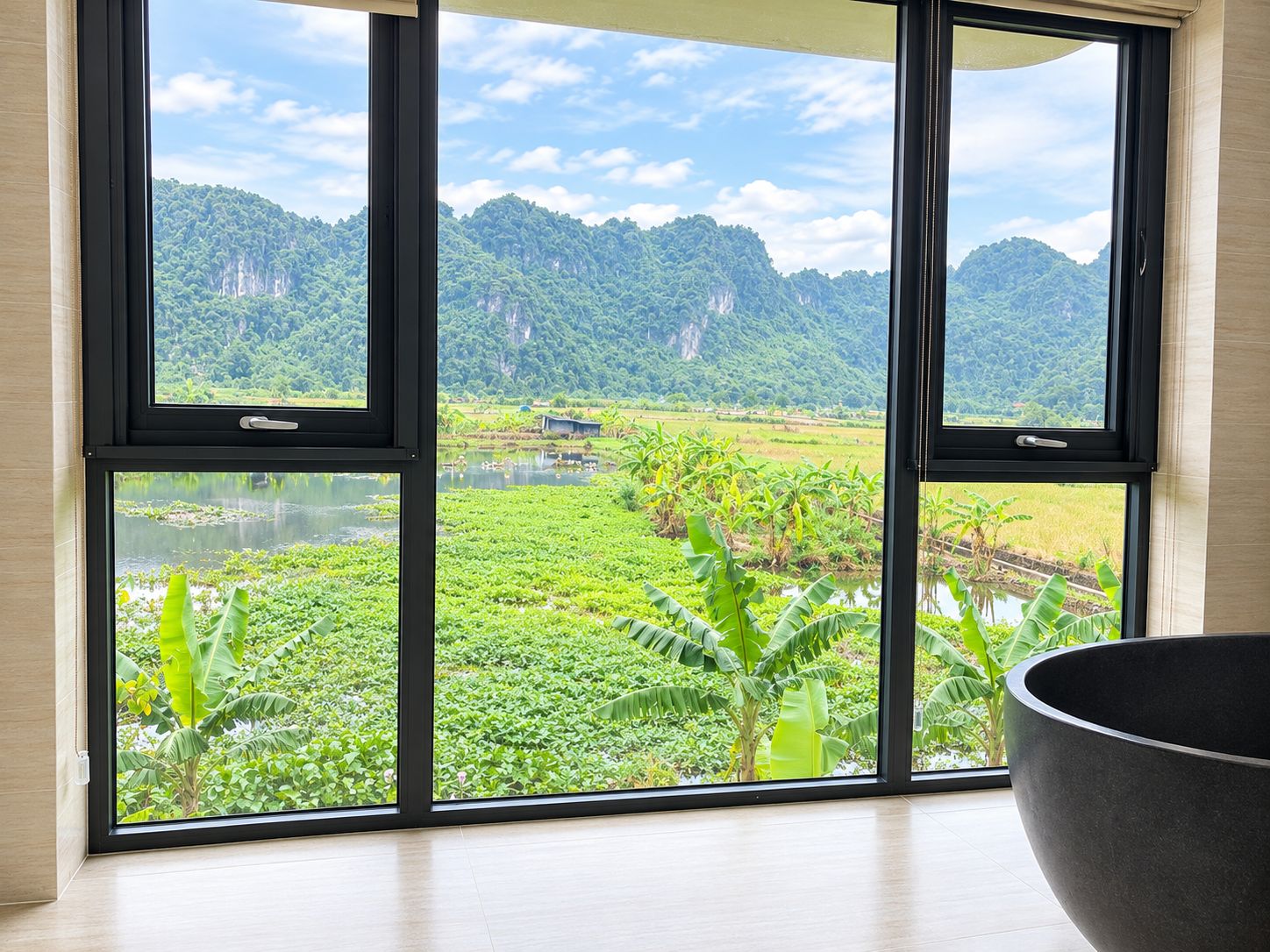 A room with a large window offering a view of a lush landscape with mountains and a river.