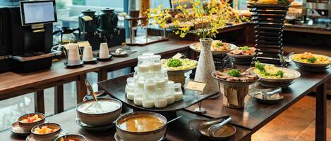 A buffet table with various food items and a coffee station.
