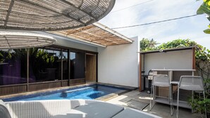 Een zwembad met ligbedden, een pergola en een overdekt zitgedeelte.