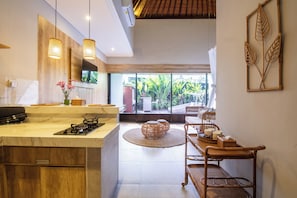 Une cuisine moderne dotée d’un grand îlot central, de luminaires suspendus et donnant sur un patio extérieur.