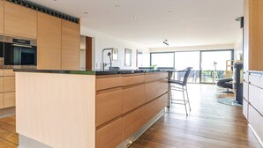 Een moderne keuken met houten kastjes, een centraal eiland en een bar met barkrukken.