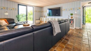 Een moderne woonkamer met een leren bank, een flatscreen televisie en een betegelde vloer.