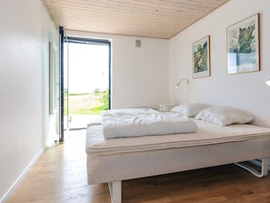 A bedroom with a bed, a bedside table, a lamp, and two framed pictures on the wall. - 4 Star Holiday Home in Frederikshavn (Frederikshavn)