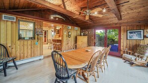 A wooden cabin interior with a dining table, chairs, a ceiling fan, and a view of the outdoors.