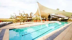 Ein Pool mit Sonnensegel, Sitzgelegenheiten im Freien und Blick auf die umliegende Landschaft.