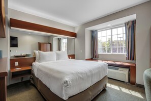 Hotelkamer met een groot bed, bureau, stoel, raam met gordijnen en een ingebouwde verwarming.