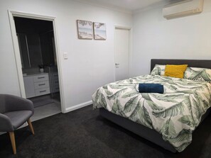 Een slaapkamer met een bed, een stoel, een kledingkast en een deur.