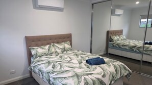 Et soveværelse med seng, et spejl og en aircondition.