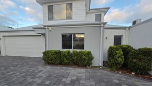 Et moderne hus med to etager, garage, indkørsel og velplejede hække.