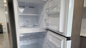 Et åbent køleskab med flere hylder og et fryserum.