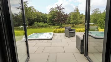 A patio area with a hot tub, outdoor seating, and a view of the garden.