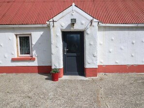 Een gebouw met een rood dak, een zwarte deur en een klein raam met een rode omlijsting.
