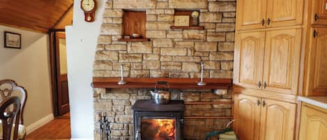 A rustic interior with a stone fireplace, wooden cabinets, and a clock on the wall.