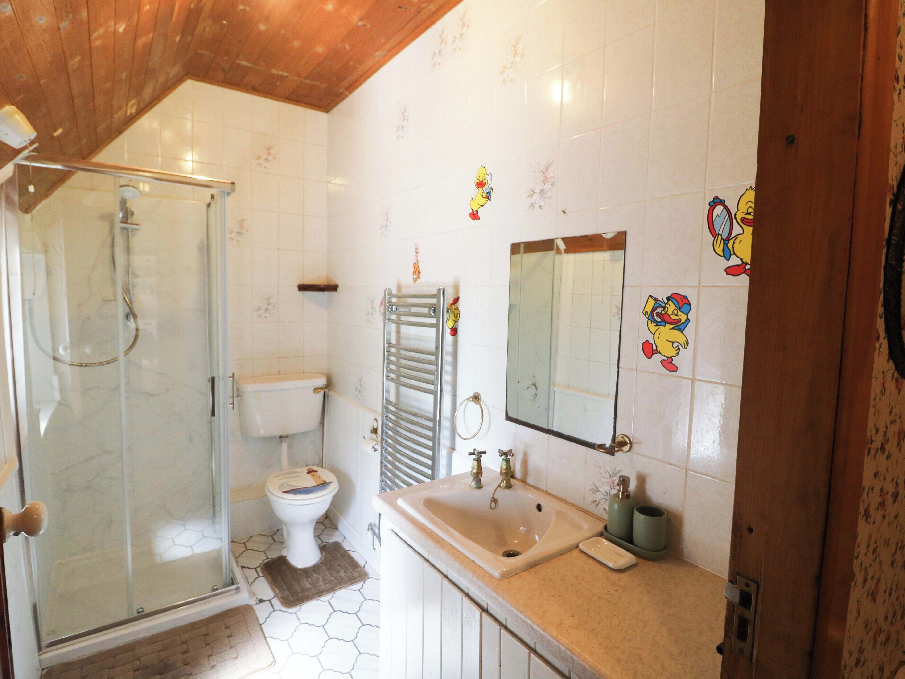 A bathroom with a shower, toilet, sink, and mirror.