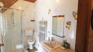 A bathroom with a shower, toilet, sink, and mirror.