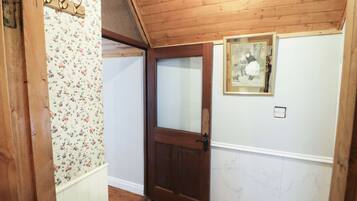 A wooden interior with a door, floral wallpaper, and a framed picture on the wall.