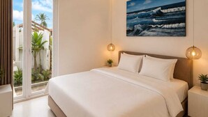 Ein Schlafzimmer mit einem großen Bett, Blick auf den Ozean durch eine Schiebetür und einem Gemälde von Wellen an der Wand.